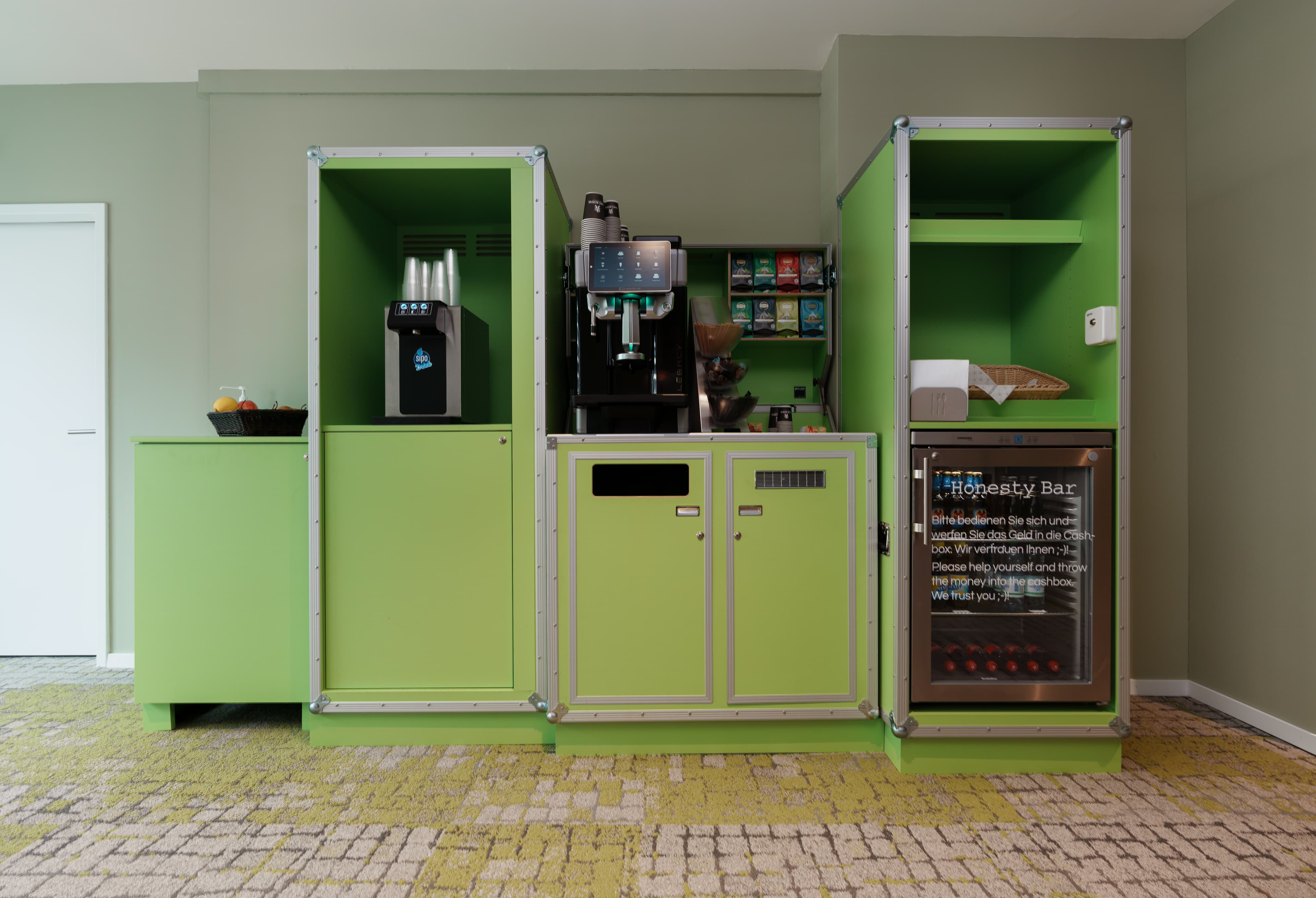 Green breakfast buffet at Flex Motel Wil with beverage dispenser, coffee machine, and honesty bar.