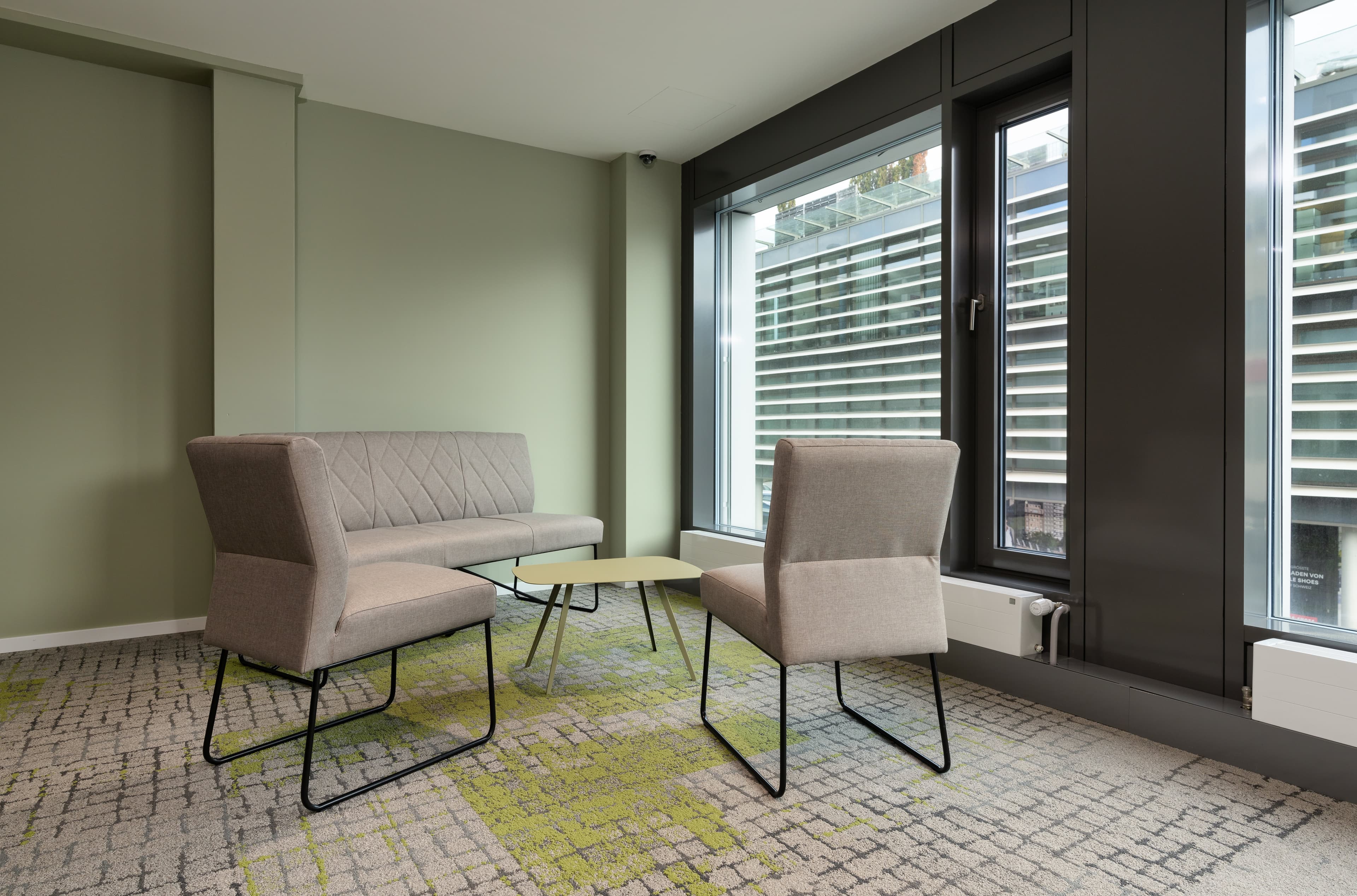 A seating area in the Flex Motel Wil with a sofa two chairs and a small table in front of large windows