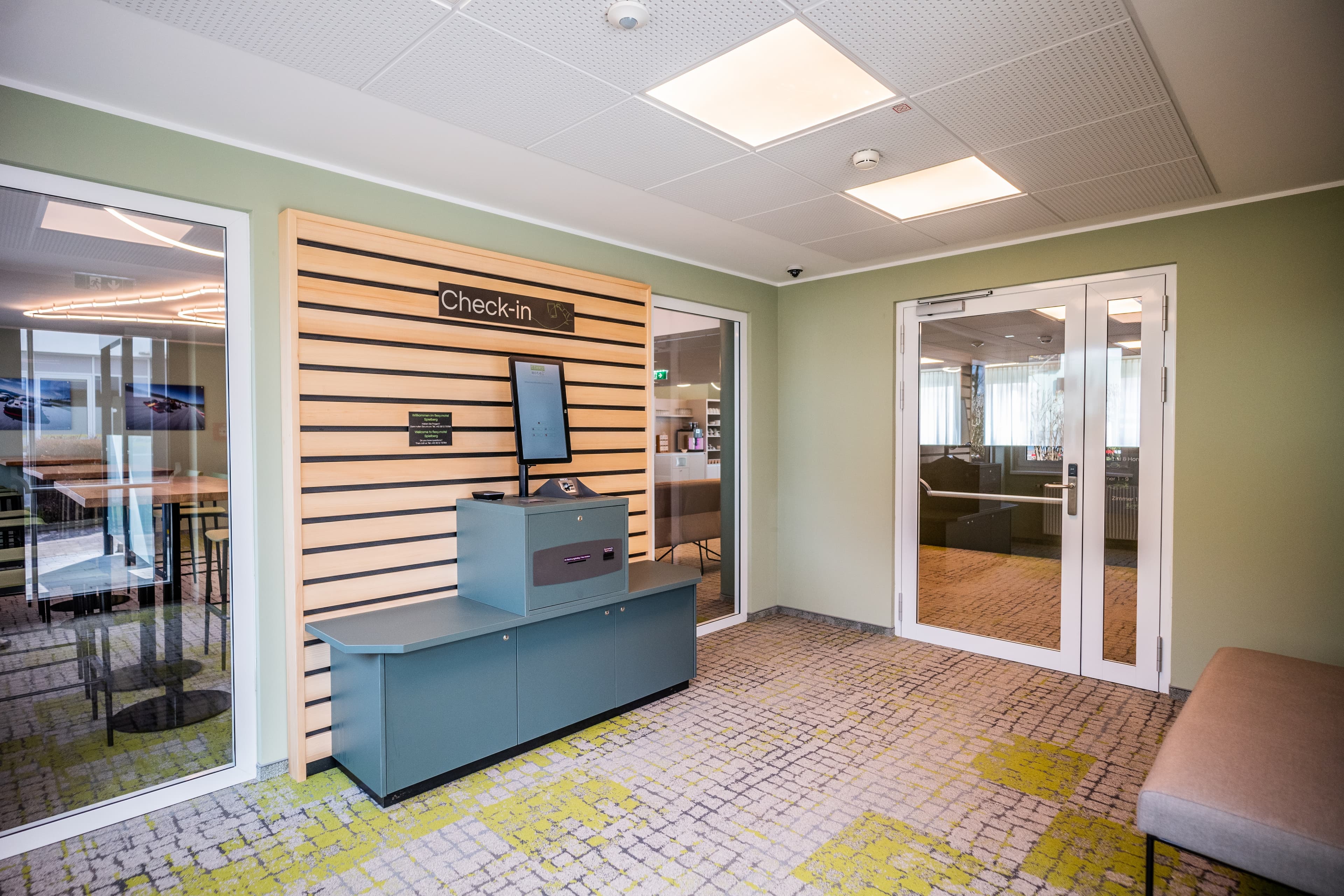 Self-service reception at the Flex Motel Spielberg with a check-in terminal and seating area