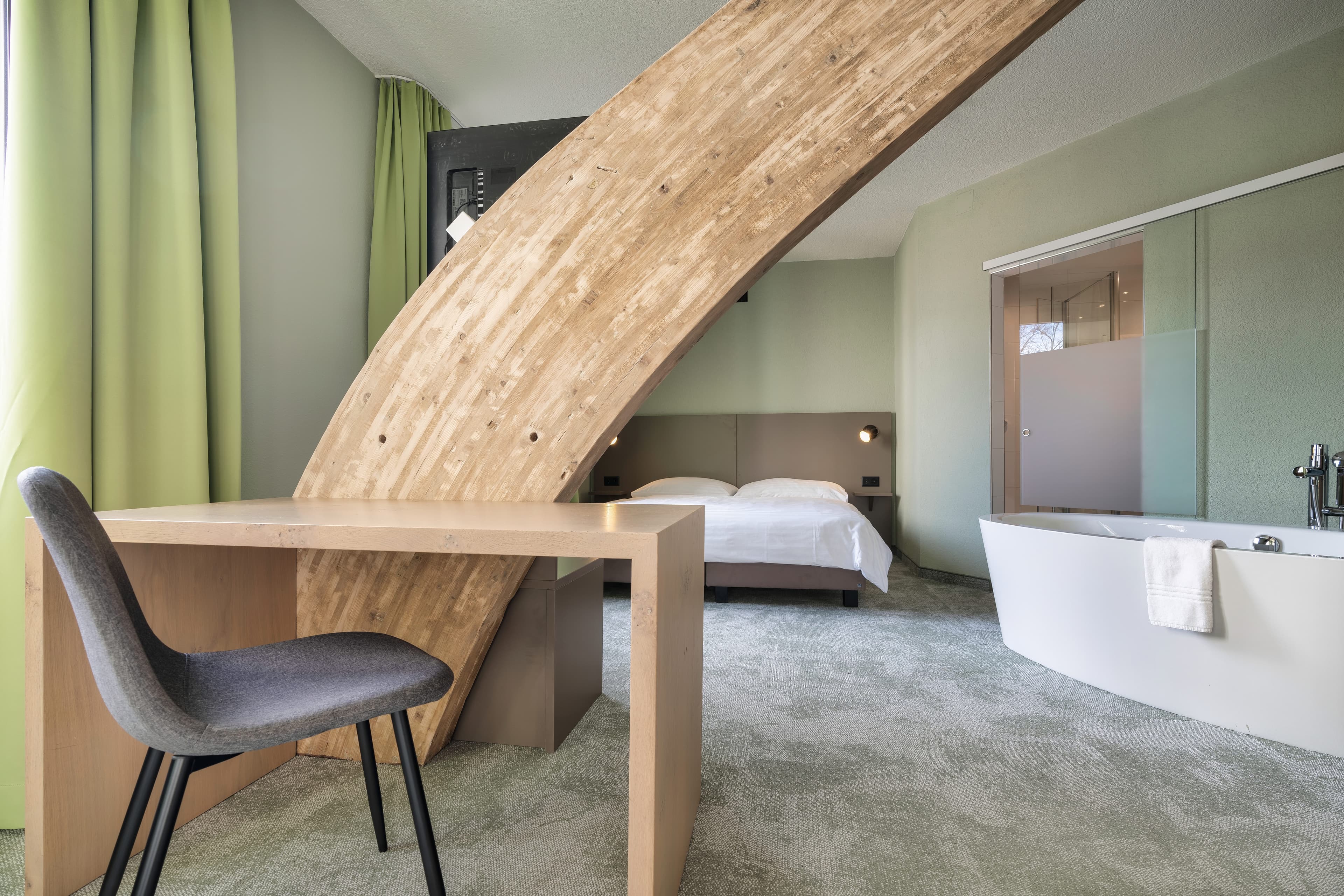 A modern hotel room in the Flex Motel Schonenwerd with a desk, a chair, a bed, and a freestanding bathtub