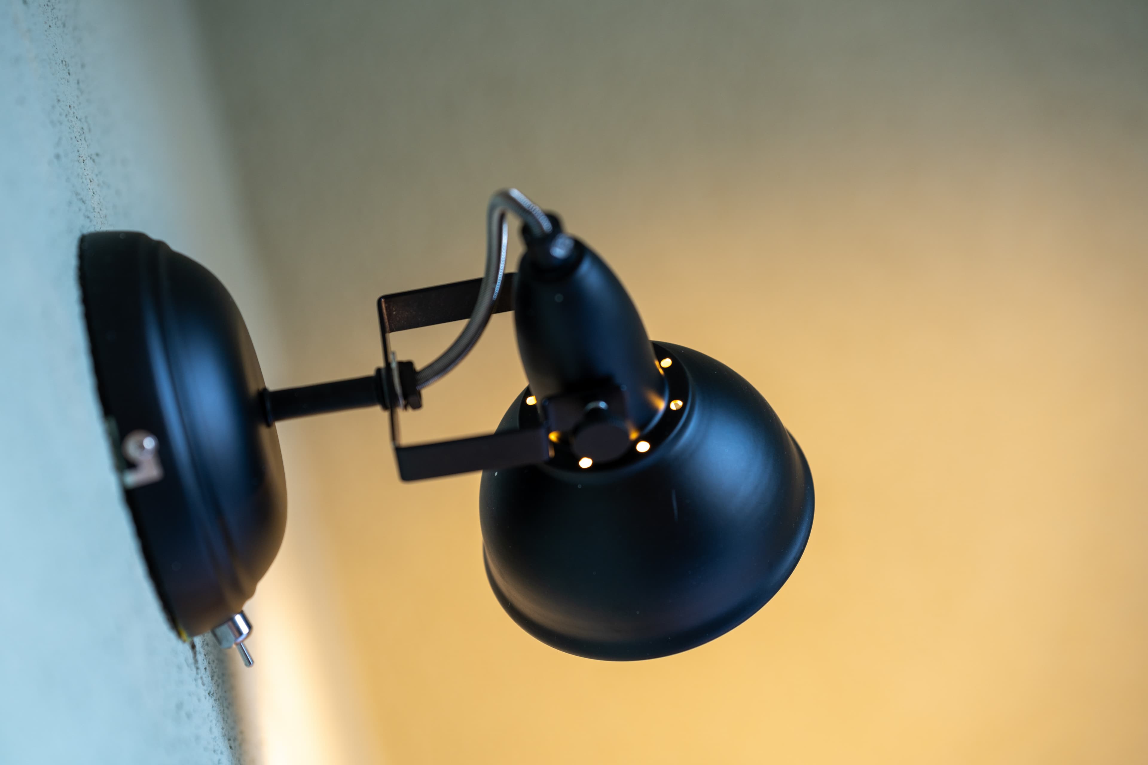 A black wall lamp in a room of the junior suite at the Flex Motel Schonenwerd is attached to a yellow wall.