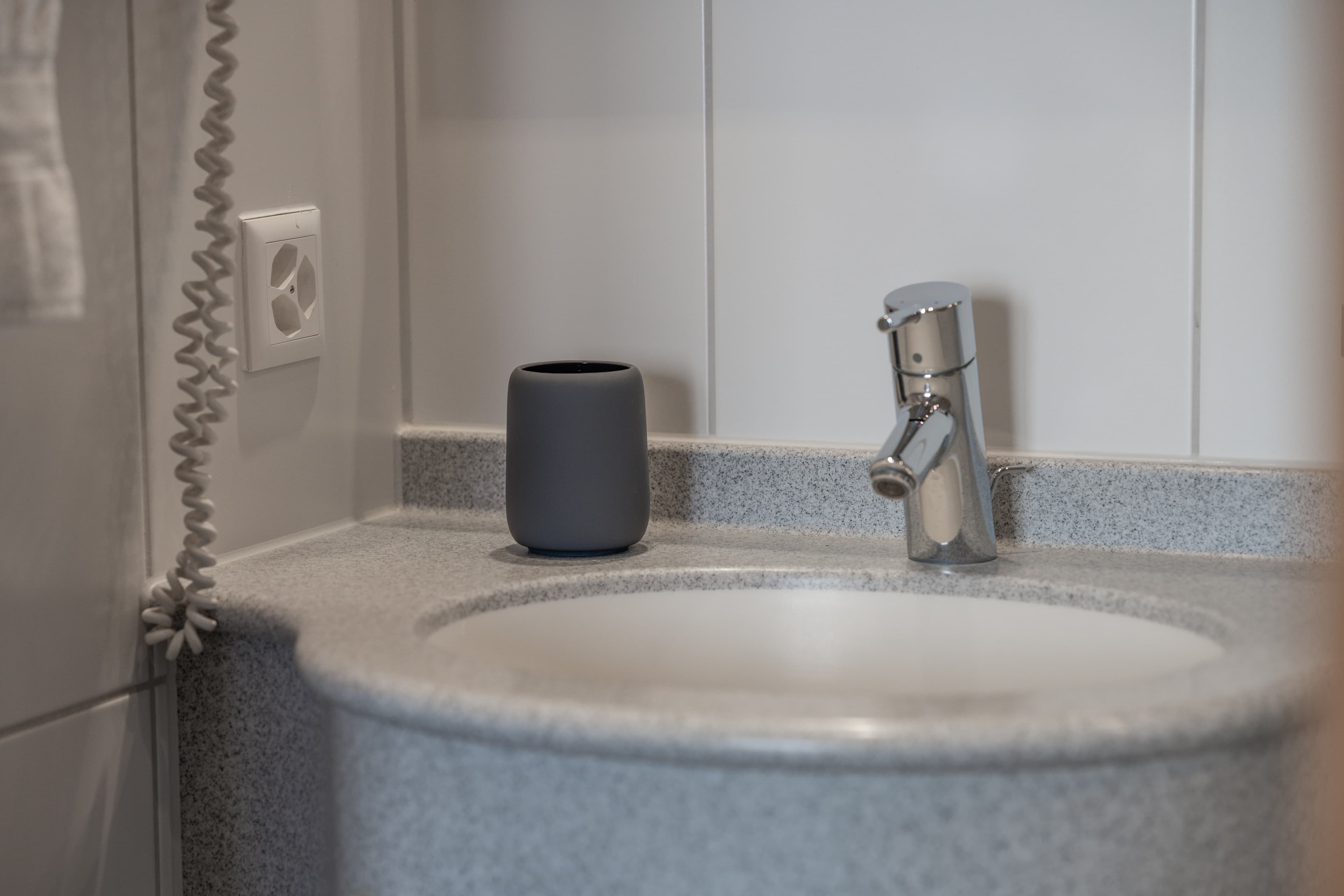 Sink with gray cup and faucet in the bathroom of a twin double room in Flex Motel Schonenwerd