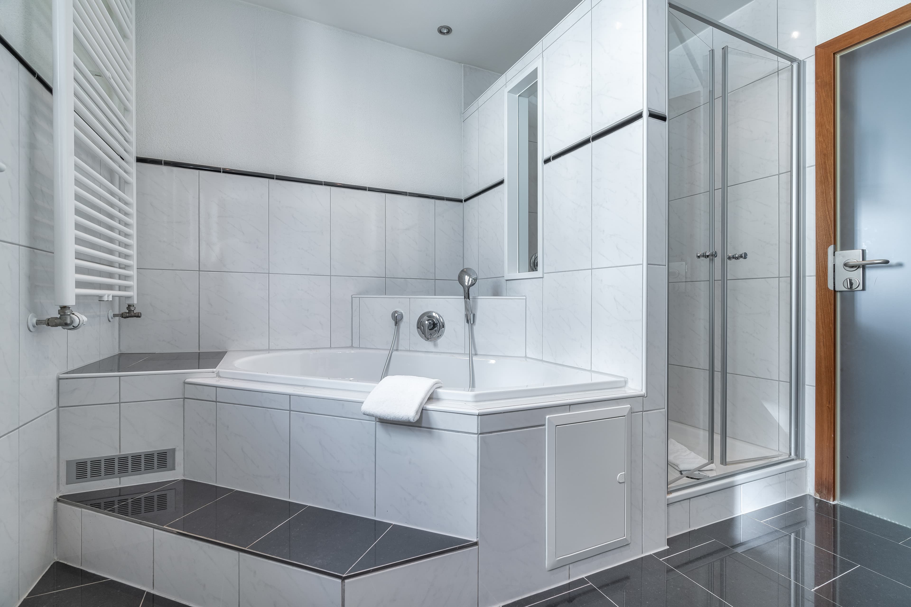 A modern bathroom view of the Junior Suite at Flex Motel Schonenwerd with bathtub shower and towel.
