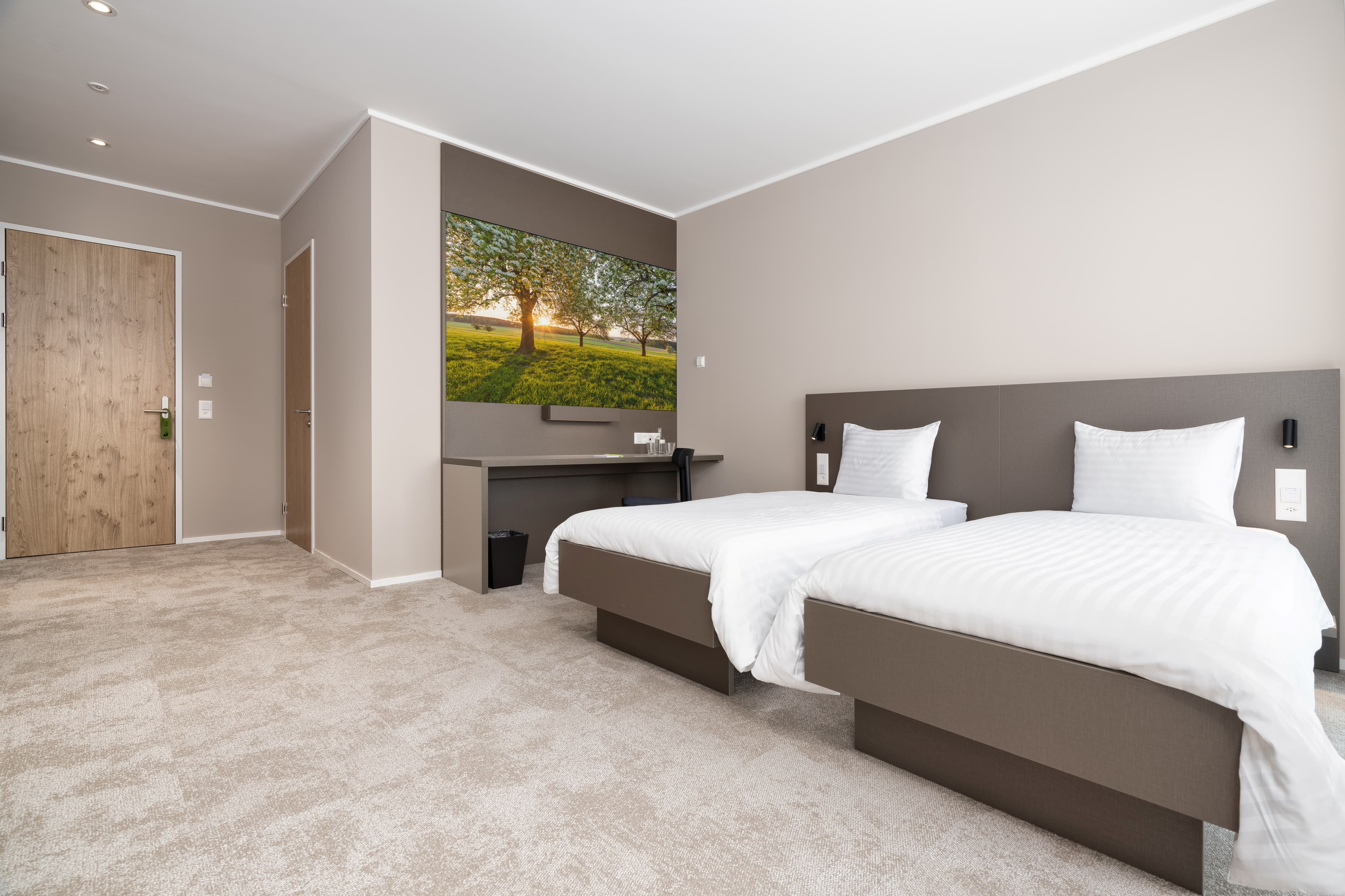 A Comfort Double Room at B Smart Motel Amriswil with two twin beds, a desk, and a large landscape picture on the wall.